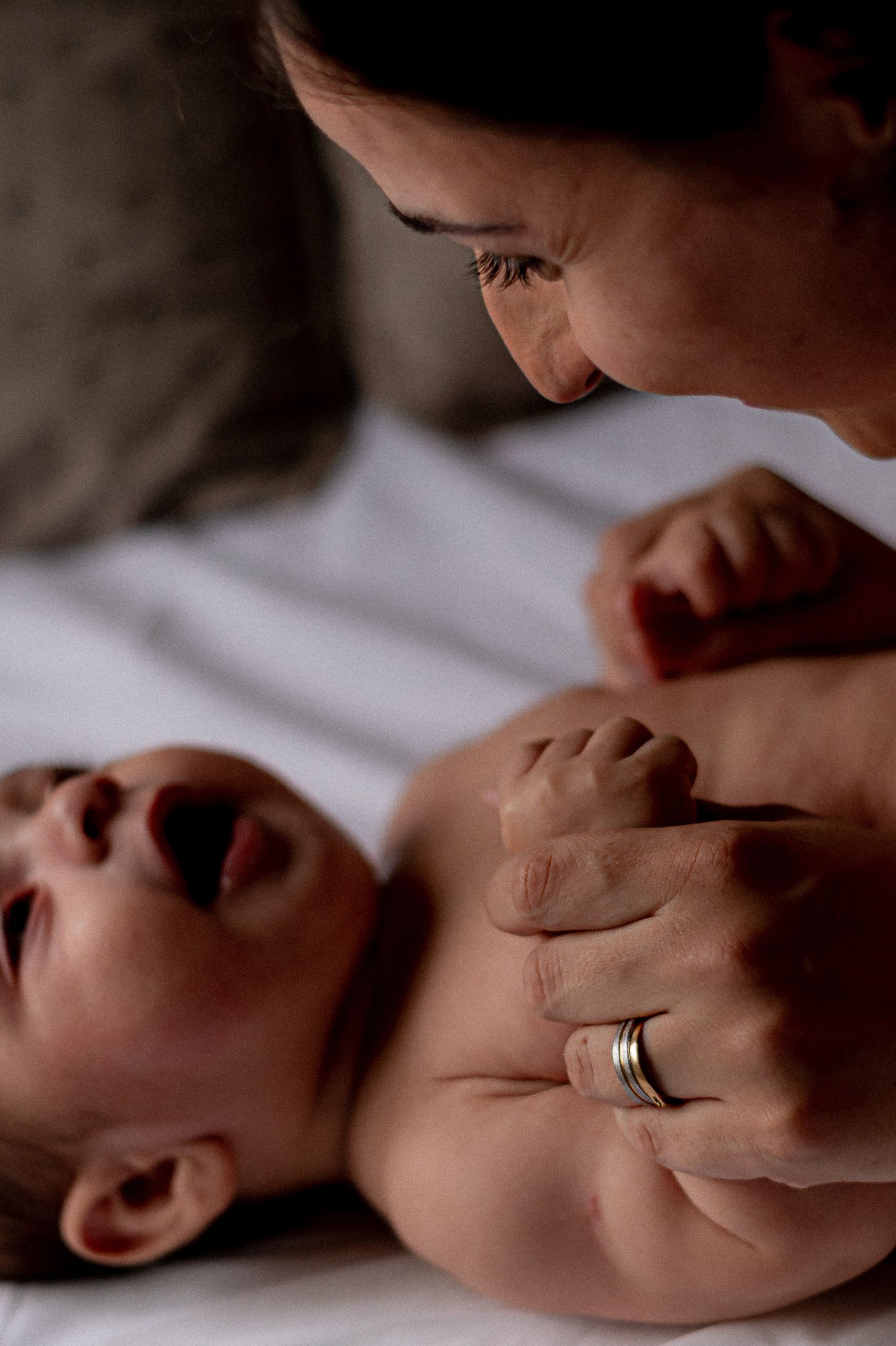 Baby grasping an adult's finger, face close to face