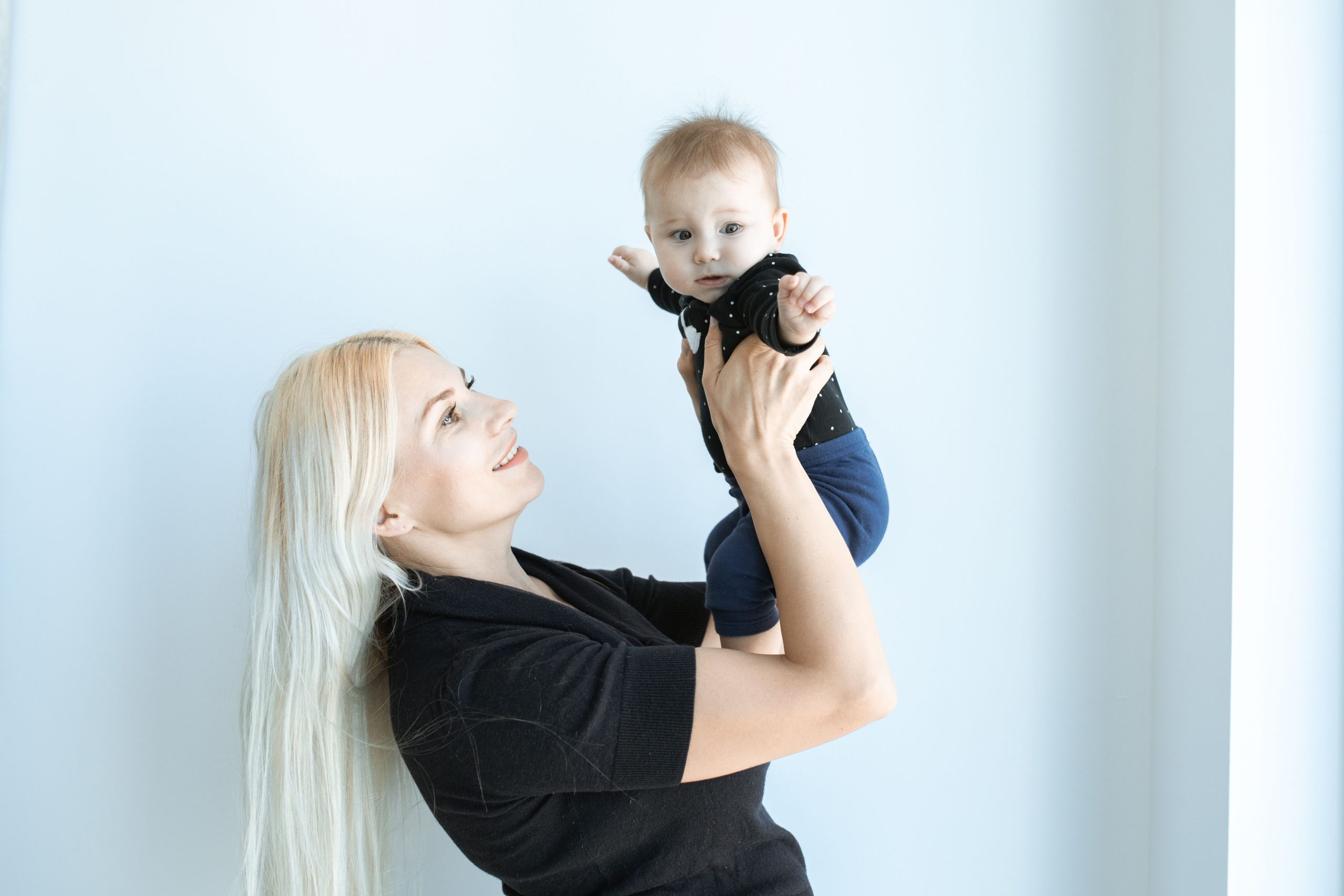 Adult smiling while gently lifting a baby