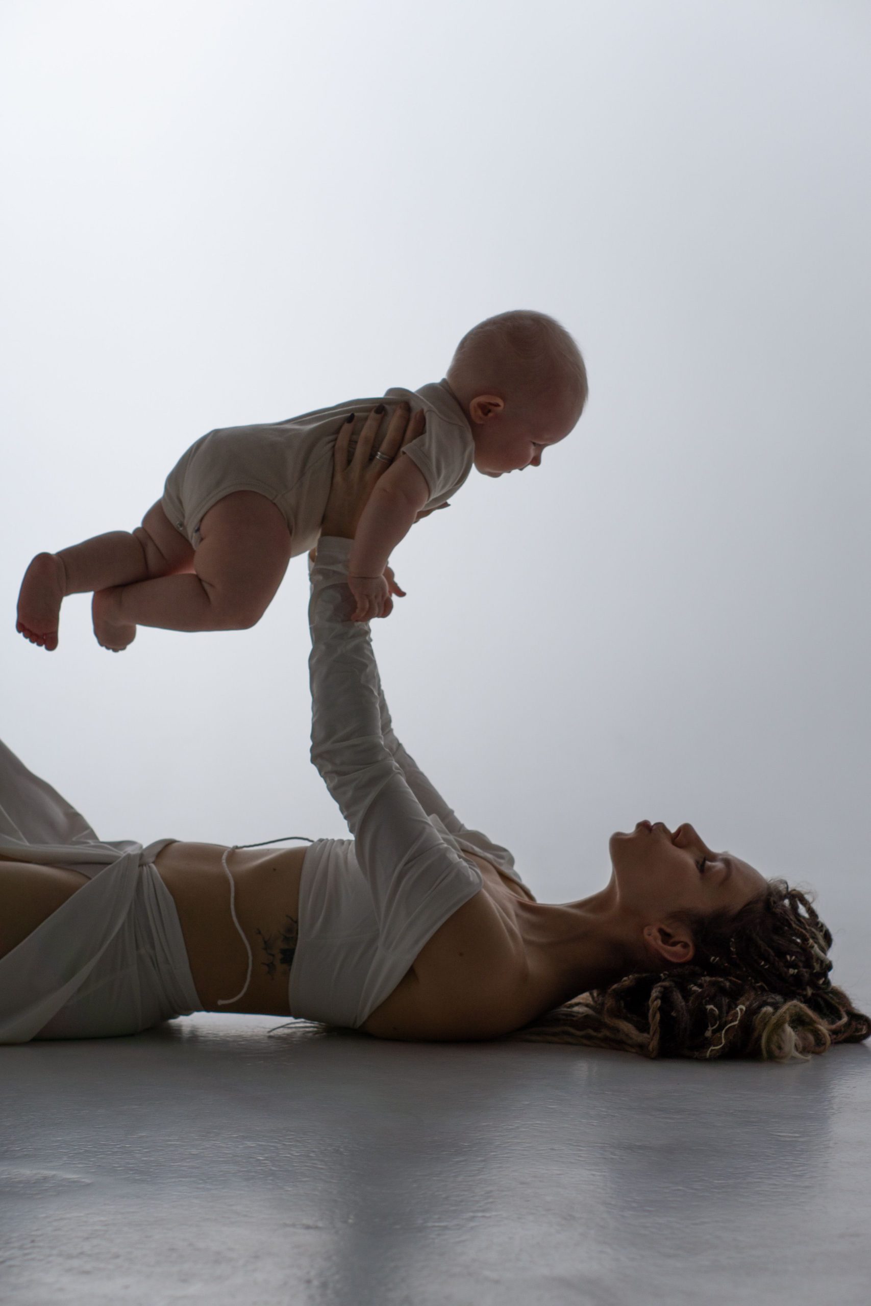 Parent lying down, lifting baby playfully overhead